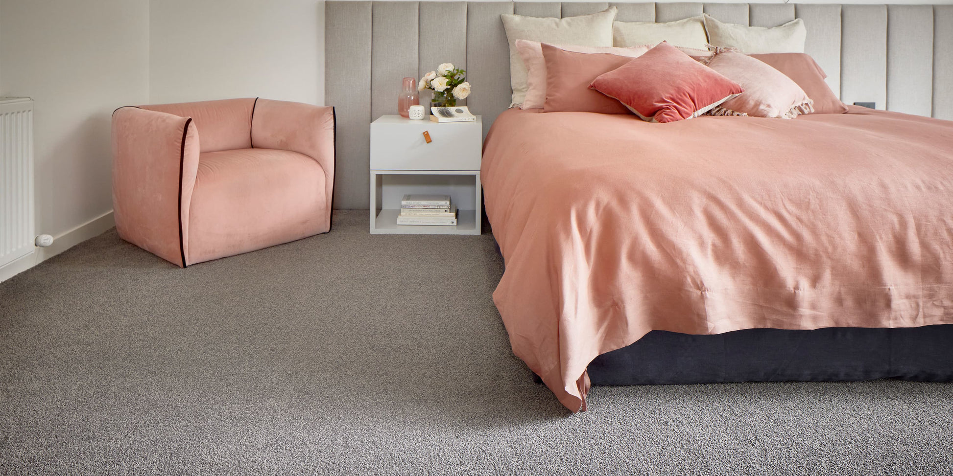 Bedroom with pink bedspread and armchair on gray carpet