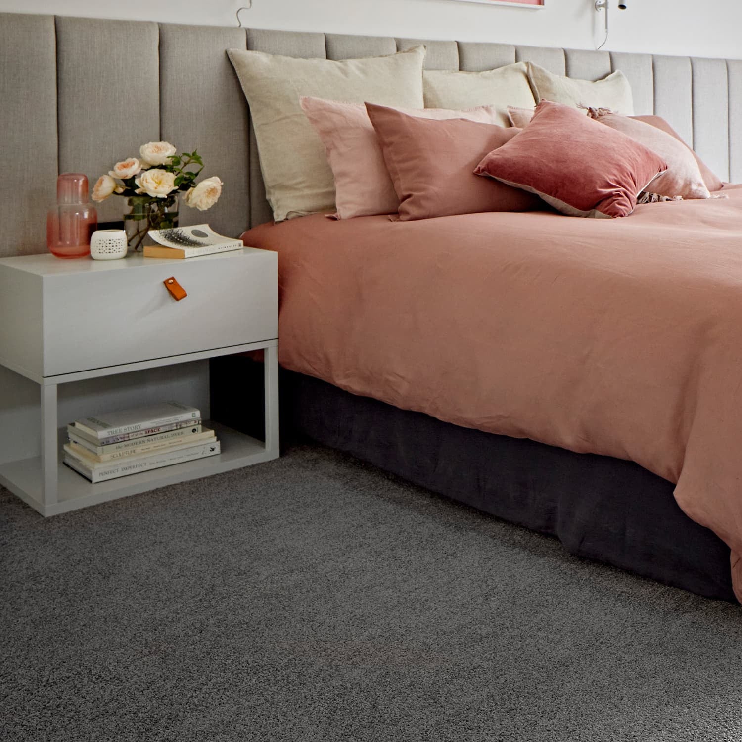 Bedroom with pink bedding and a matching armchair, featuring grey carpet called Beacon from Supreme Touch.